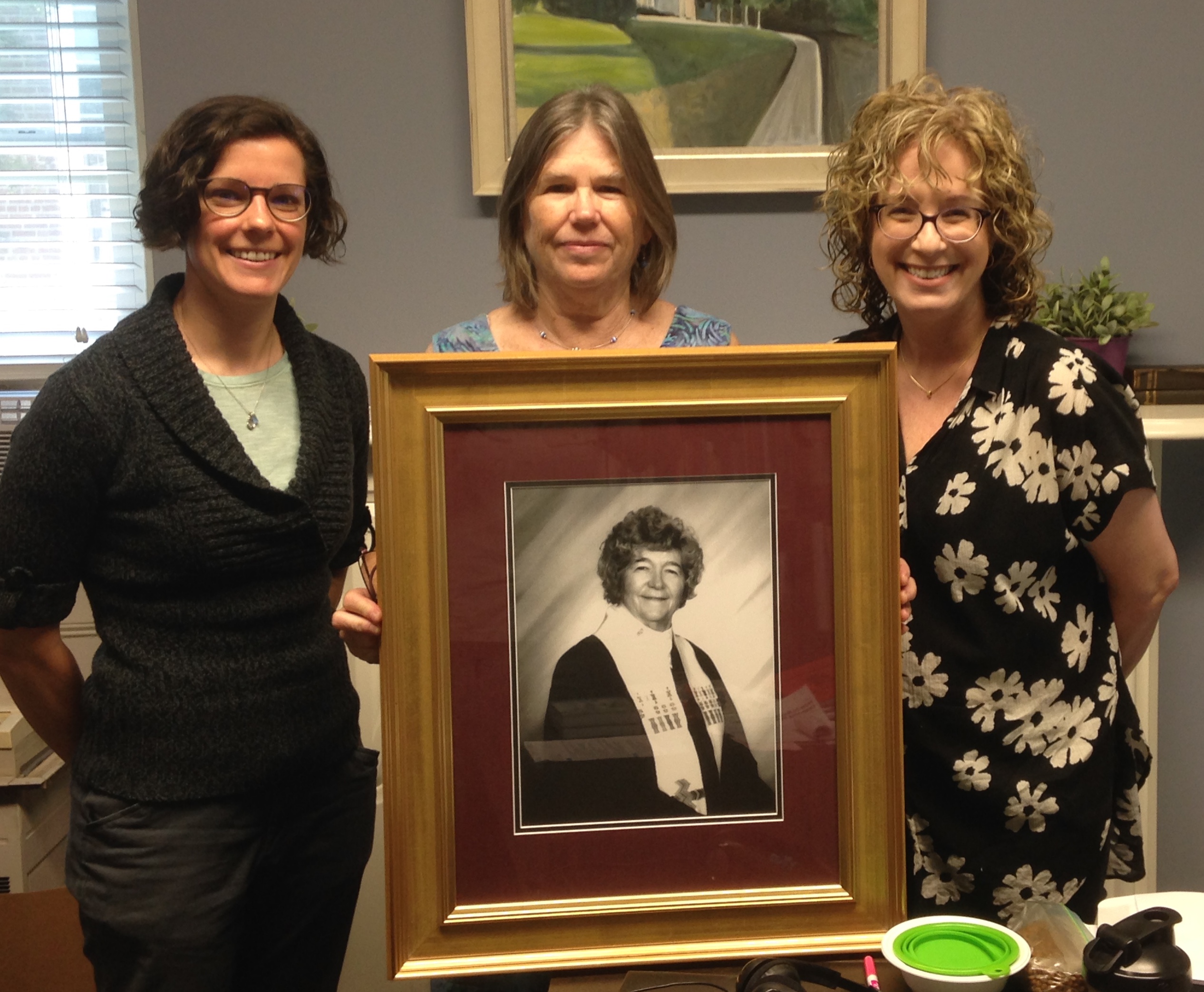Pictured above: Photo of Rev. Joyce Stedge held by Debbie Stedge, standing with Rev. Amy Nyland and Rev. Julia Doellman-Brown